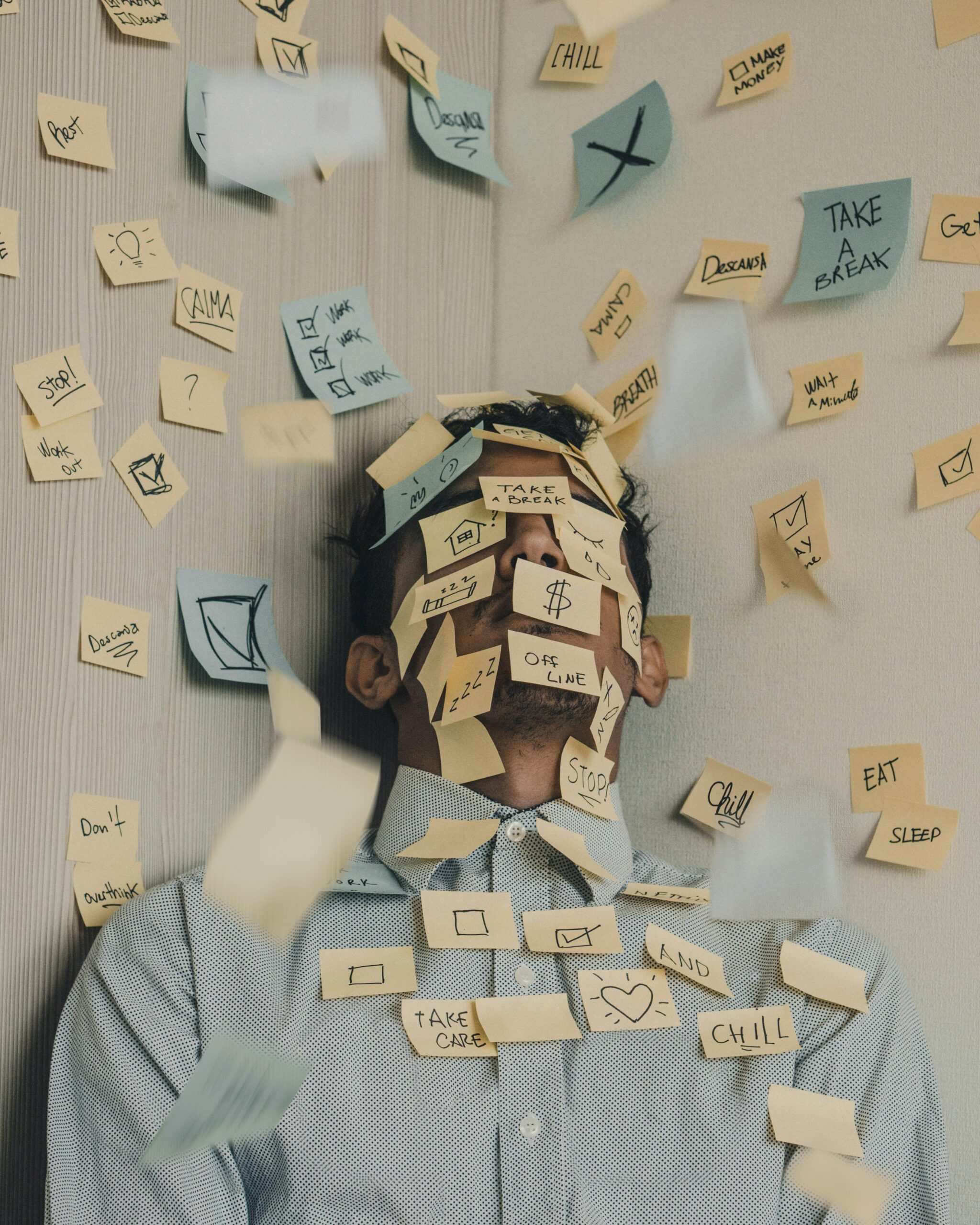 Homme débordé professionnellement recouvert de post-its jaunes et bleus.